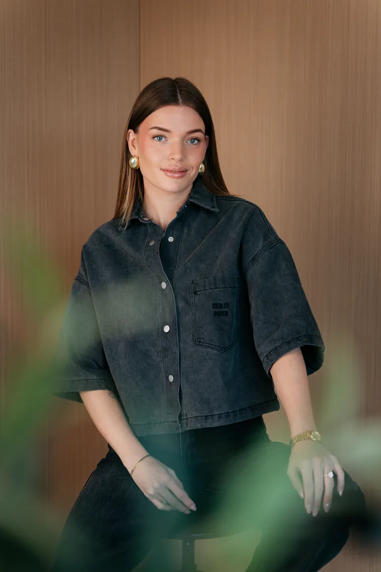 Portret van Eline Vera in een donker denim overhemd, kijkend in de camera